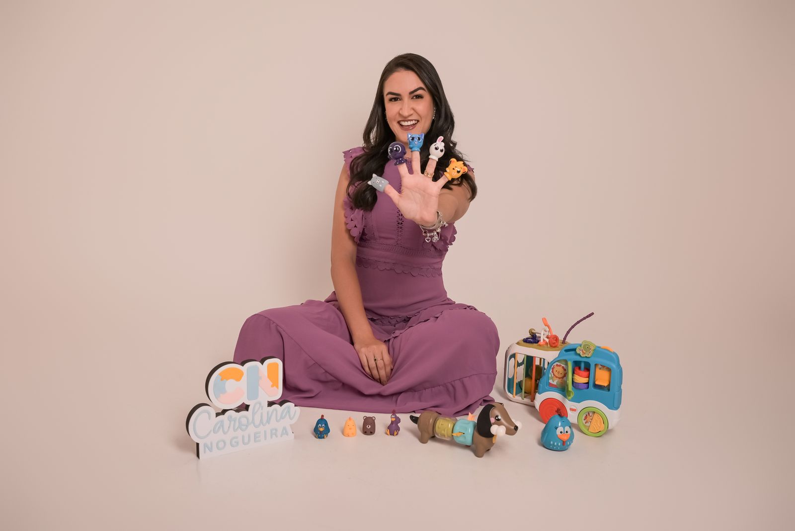 Dra. Carol sentada no chão entre brinquedos